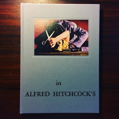 Capa de livro cinzenta clara com foto colorida e texto 'in ALFRED HITCHCOCK'S'