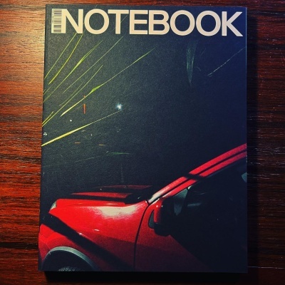 Capa de caderno com carro vermelho à noite e texto 'NOTEBOOK'