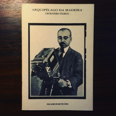 Capa de livro com foto a preto e branco de homem com câmara de filmar, texto 'ARQUIPÉLAGO DA MADEIRA UM ROTEIRO FÍLMICO'
