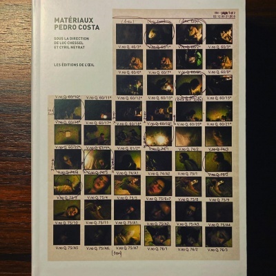 Capa de livro com imagens pequenas e texto em francês sobre mesa de madeira