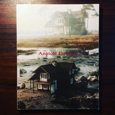 Capa de livro com casas em cenário costeiro e texto Anatole Dauman