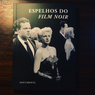 Capa de livro preto com título 'ESPELHOS DO FILM NOIR' e imagem em preto e branco de homem e mulher elegantes