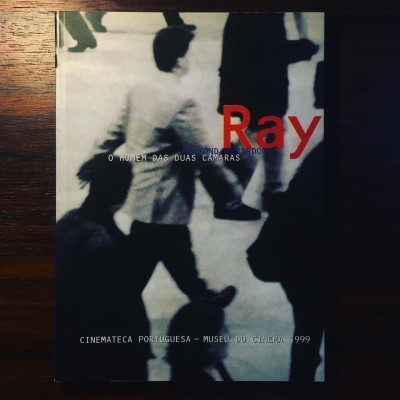 Capa de livro com pessoas desfocadas a andar e texto vermelho e branco