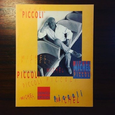 Capa amarela com foto a preto e branco de homem sentado, textos MICHEL PICCOLI e CINEMATECA PORTUGUESA