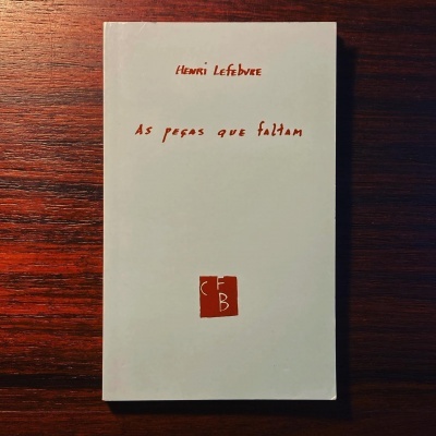 Livro 'As peças que faltam' de Henri Lefebvre com capa branca e texto vermelho sobre mesa de madeira.