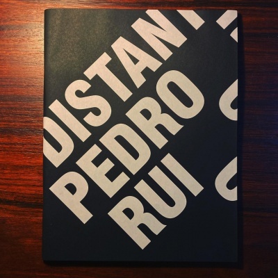 Livro com capa preta e letras brancas em superfície de madeira