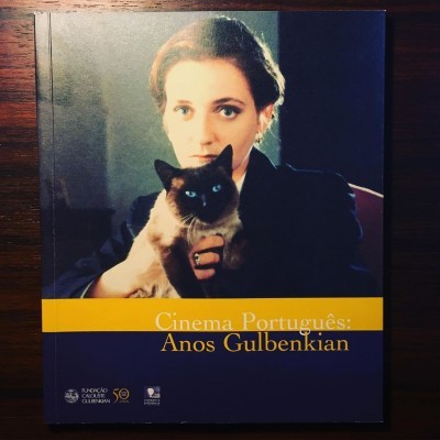 Livro 'Cinema Português: Anos Gulbenkian' com capa azul e amarela e fotografia de mulher com gato siamês.