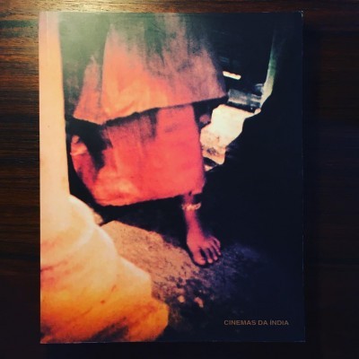 Livro com capa fotográfica mostrando pernas de pessoa com tecido vermelho e bege e texto CINEMAS DA ÍNDIA