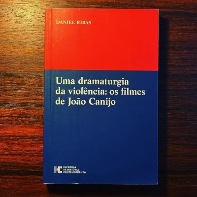 Livro com capa vermelha e azul sobre superfície de madeira escura
