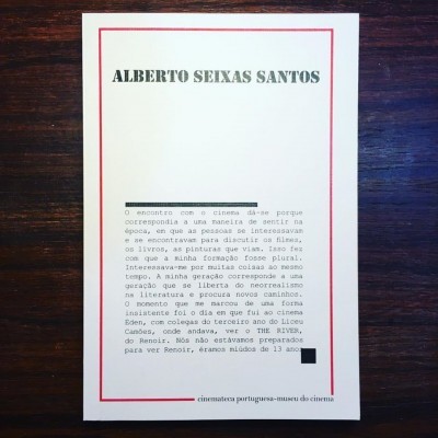 Capa de livro branca com texto preto e borda vermelha sobre mesa de madeira.