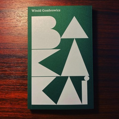 Capa de livro verde com título branco em formas geométricas sobre madeira escura