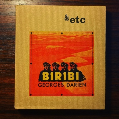 Caixa castanho claro com etiqueta vermelha e preta B1R1B1 GEORGES DARIEN e texto &etc