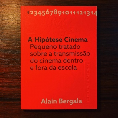 Livro vermelho 'A Hipótese Cinema' de Alain Bergala sobre madeira escura
