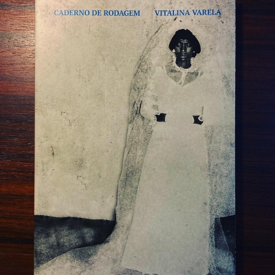 Capa de livro com foto em sépia de mulher vestida de branco e texto azul no topo