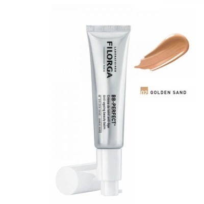 Tubo prateado de BB cream Filorga com tampa branca e amostra de cor dourada.