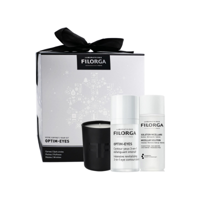Conjunto de cosméticos Filorga OPTIM-EYES com creme de olhos e solução micelar junto a uma vela preta, embalagem decorada com laço preto
