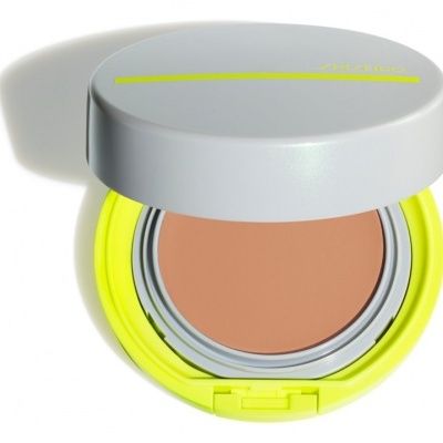 Pó compacto para rosto em embalagem redonda cinzenta e amarela com tampa aberta