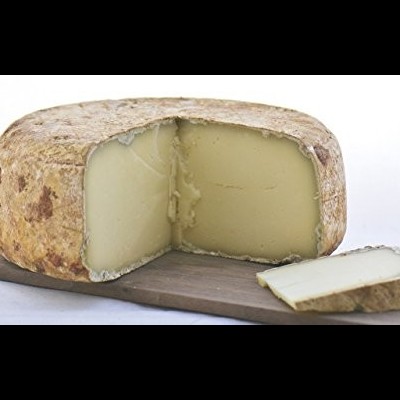 Queijo redondo com casca castanha clara e fatia cortada sobre tábua de madeira