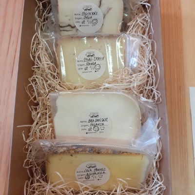 Quatro queijos embalados a vácuo em caixa de cartão com enchimento de papel