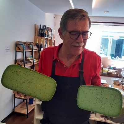 Homem com avental a segurar dois tabuleiros verdes em loja interior