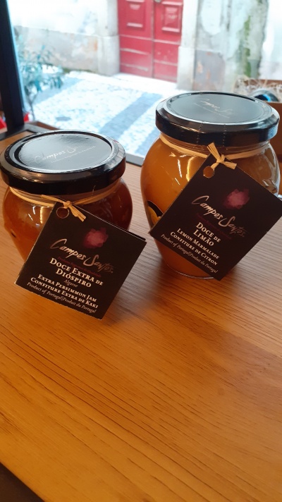 Dois frascos de compota Campos Sonhos com etiquetas pretas sobre mesa de madeira