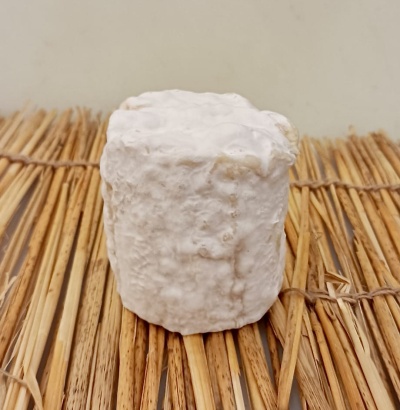 Queijo com crosta branca rugosa sobre palha amarela entrelaçada