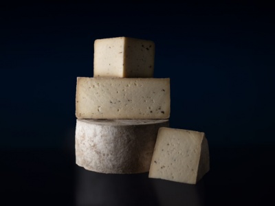 Várias peças de queijo empilhadas em fundo escuro