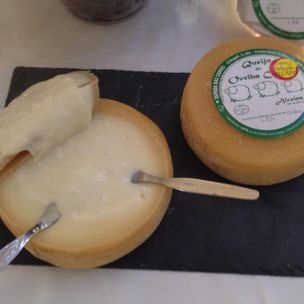 Dois queijos redondos, um aberto com faca e colher, outro fechado com etiqueta