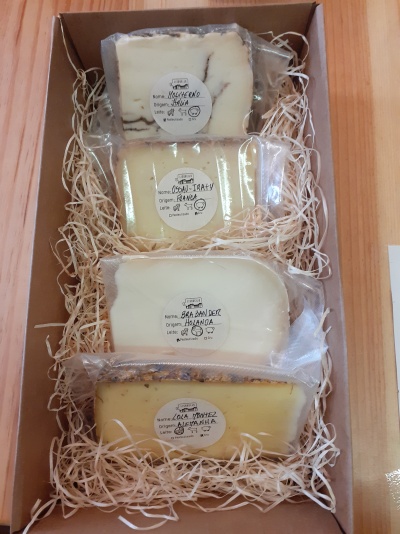 Quatro queijos embalados a vácuo em caixa de cartão com enchimento de papel