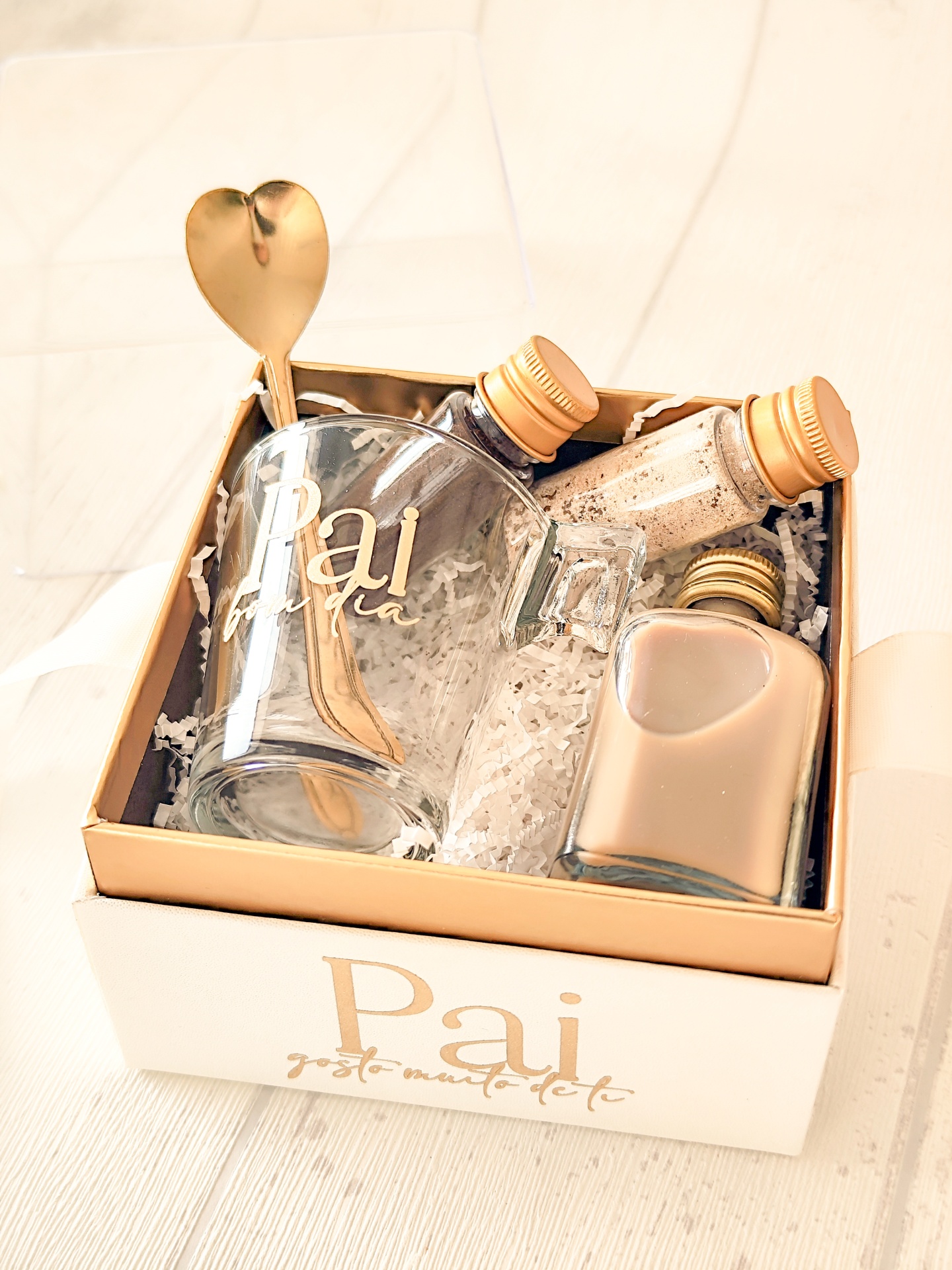 Conjunto presente festa com caneca, colher dourada, frascos e caixa branca com dourado.