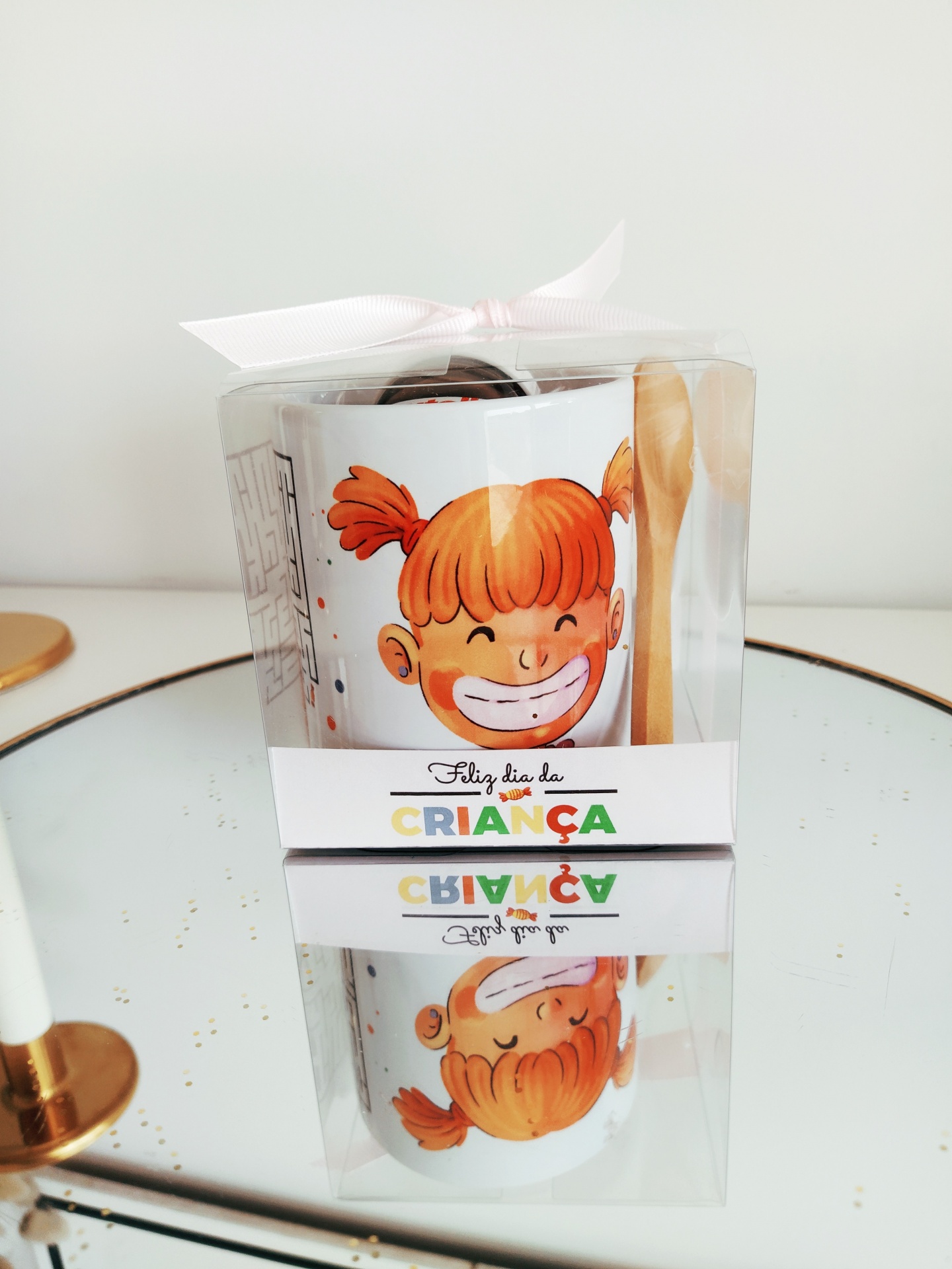Caneca branca com desenho de menina ruiva sorridente e colher de madeira em caixa transparente com laço