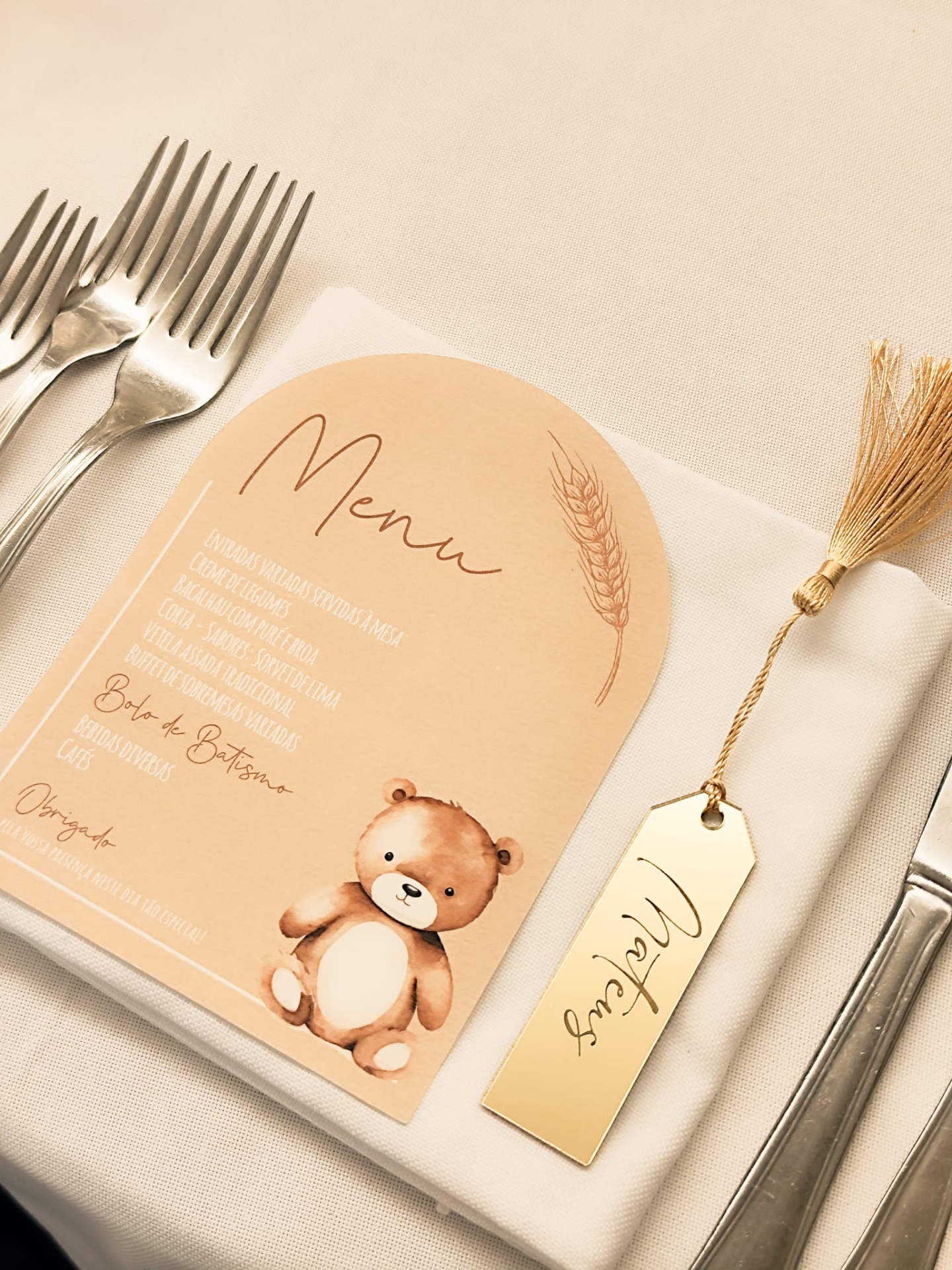 Conjunto de talheres, guardanapo branco com menu e etiqueta dourada com nome
