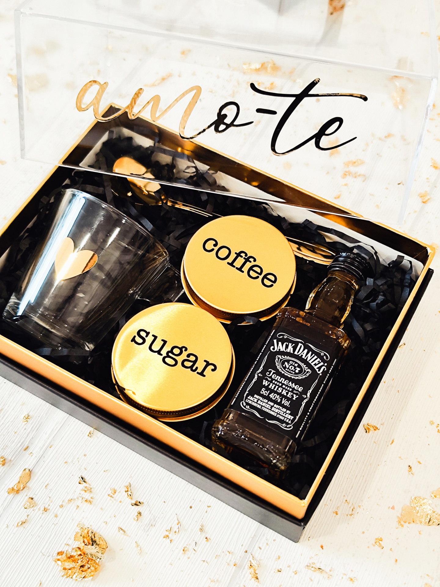 Conjunto regalo com copo, frascos, garrafa e colher em caixa preta com tampa transparente e texto amo-te