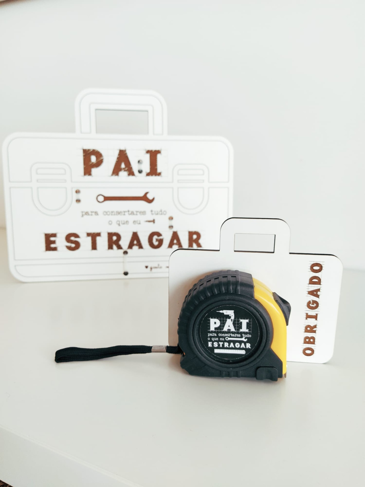 Fita métrica preta e amarela com embalagem branca em forma de maleta com texto em castanho