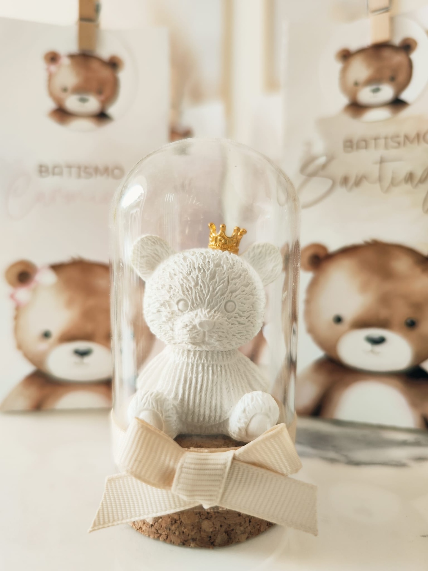 Urso branco com coroa dourada em redoma de vidro sobre base de cortiça com laço bege