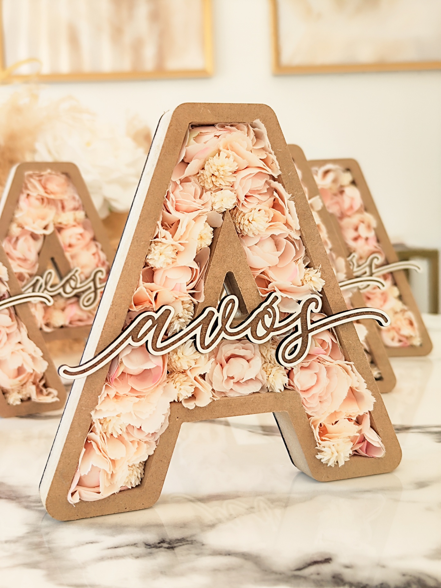 Letras decorativas A preenchidas com flores artificiais e palavra lavós