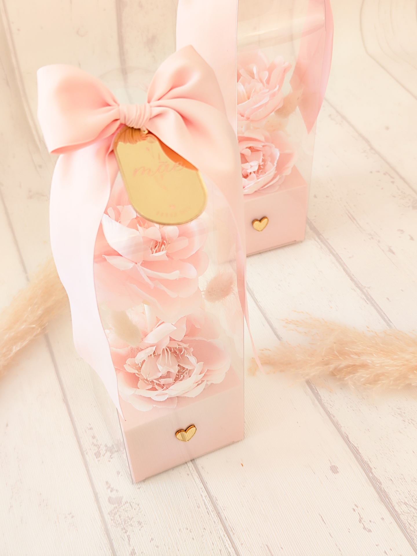Embalagem transparente com flores cor-de-rosa, laço rosa e etiqueta dourada
