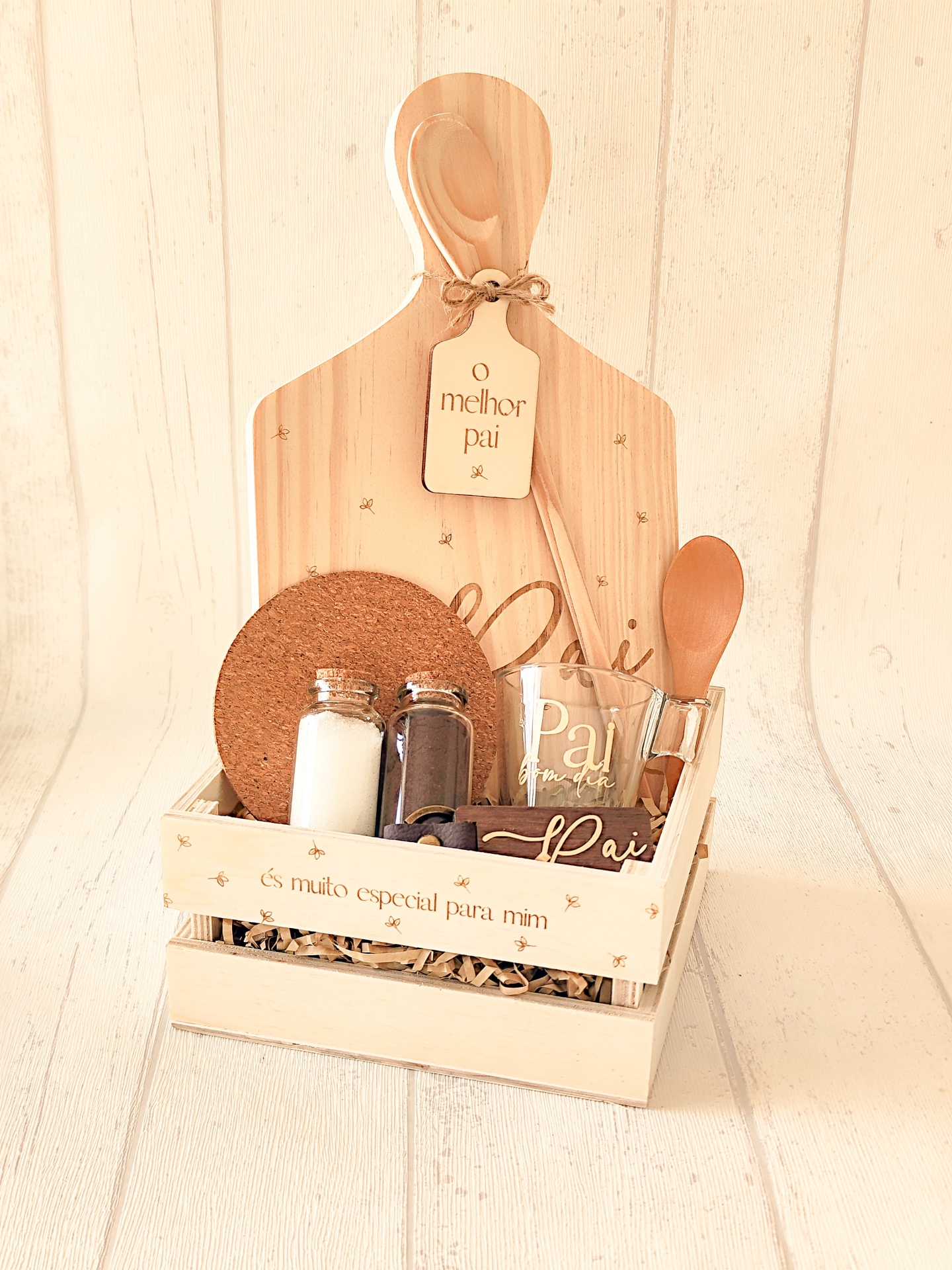 Conjunto de presente para pai com caixa de madeira, tábua de cortar, colher, garrafas com temperos, copo de vidro e texto personalizado.
