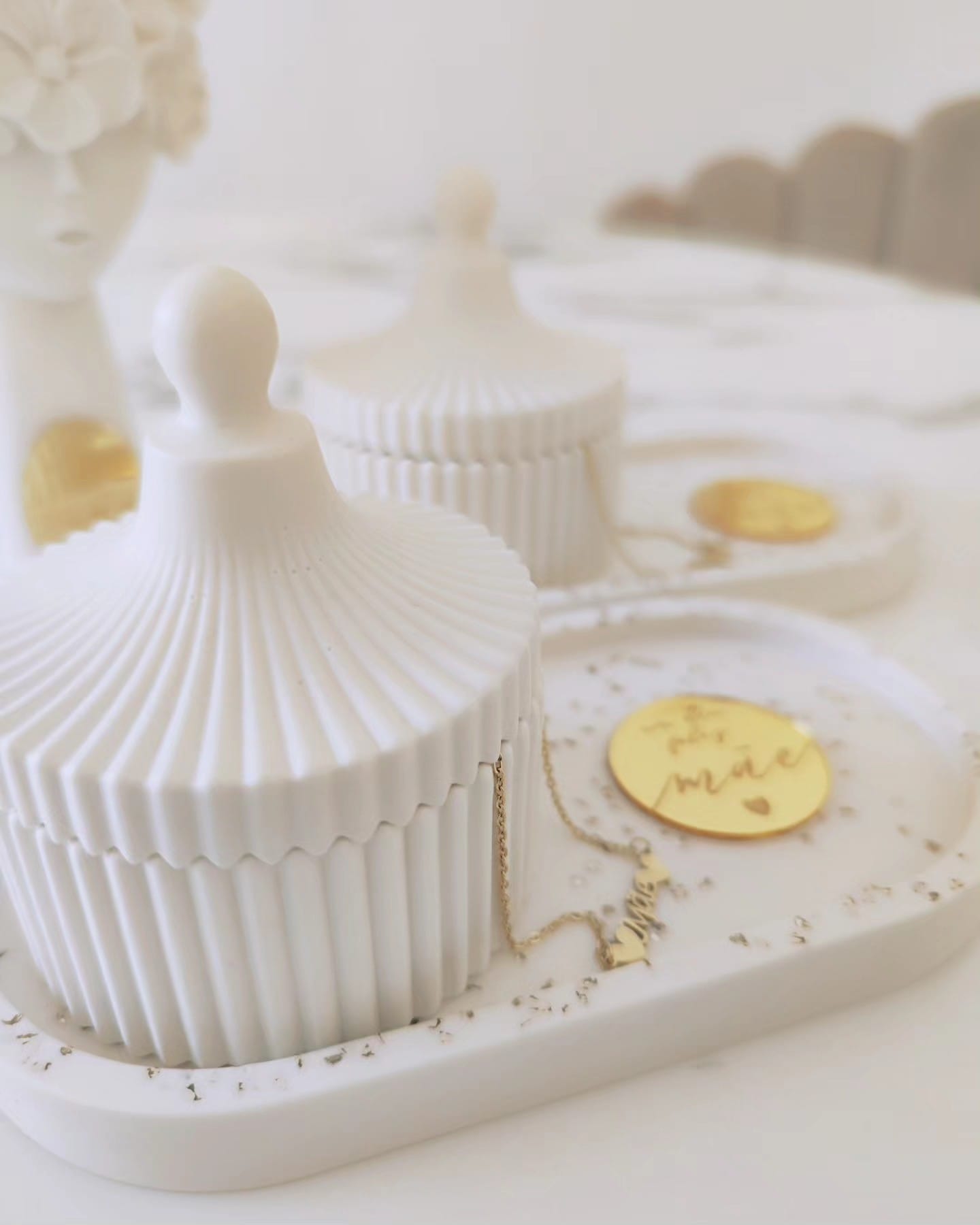 Caixas decorativas brancas em cerâmica com tampa canelada sobre bandeja branca com etiqueta dourada