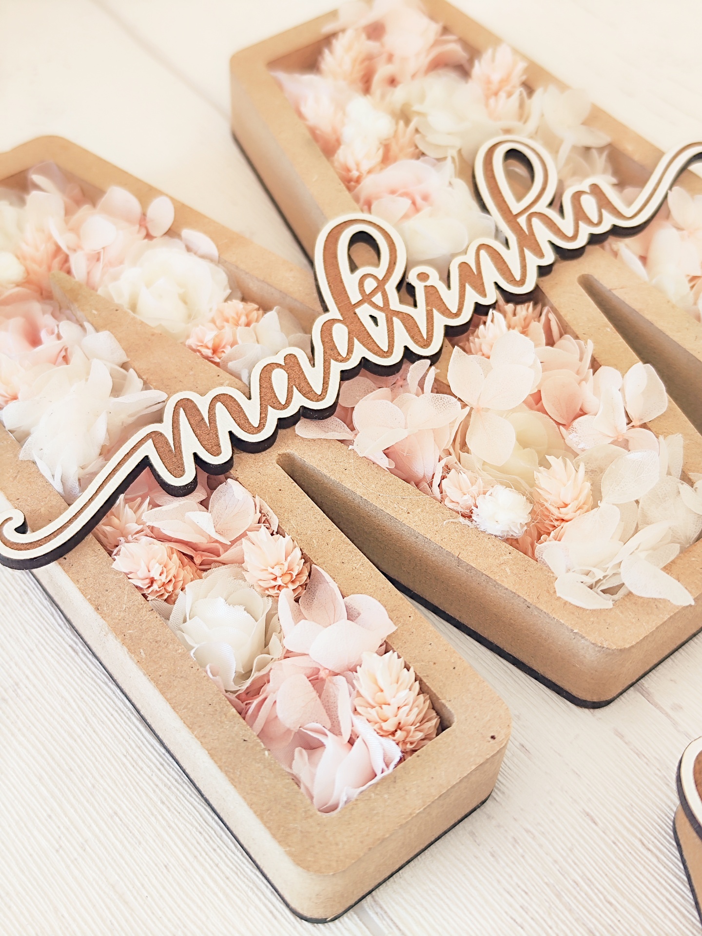 Letra decorativa M com flores artificiais rosa e brancas