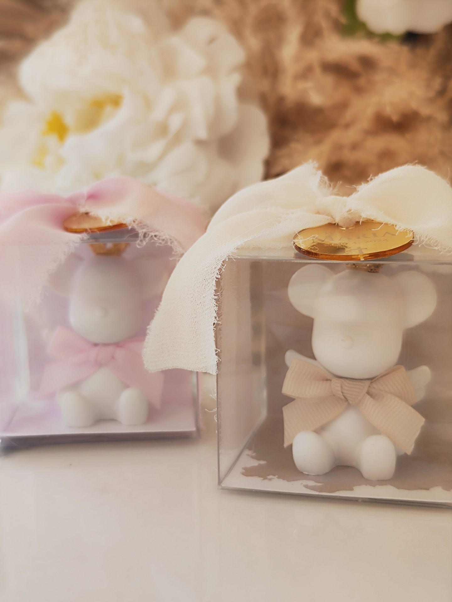 Ursinhos de cerâmica em caixas transparentes com laços de tecido rosa e bege e selo dourado