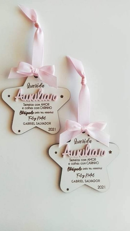 Enfeites estrela brancos com fita rosa e texto de agradecimento em português.