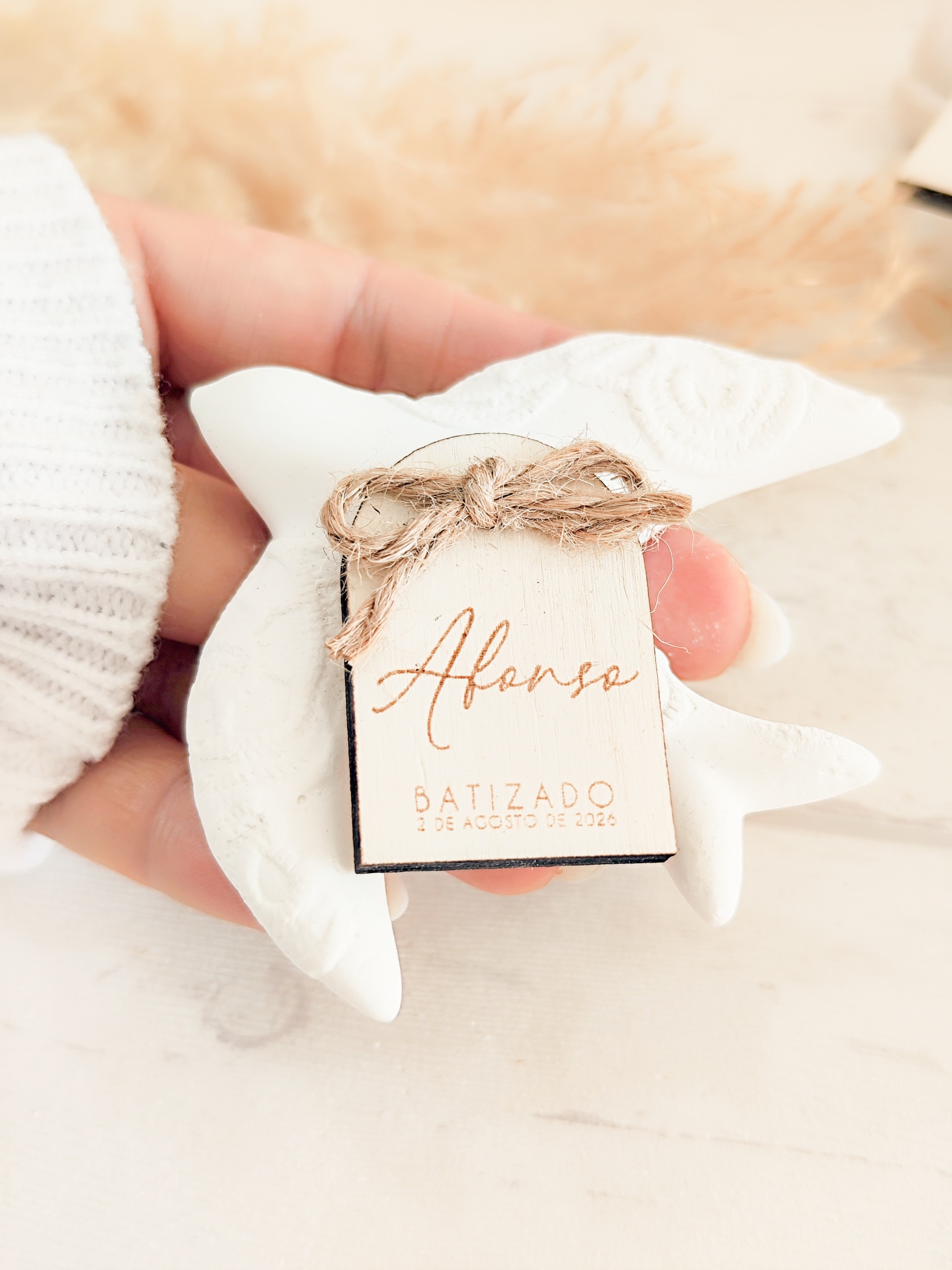 Anjo decorativo branco com etiqueta de batizado amarrada
