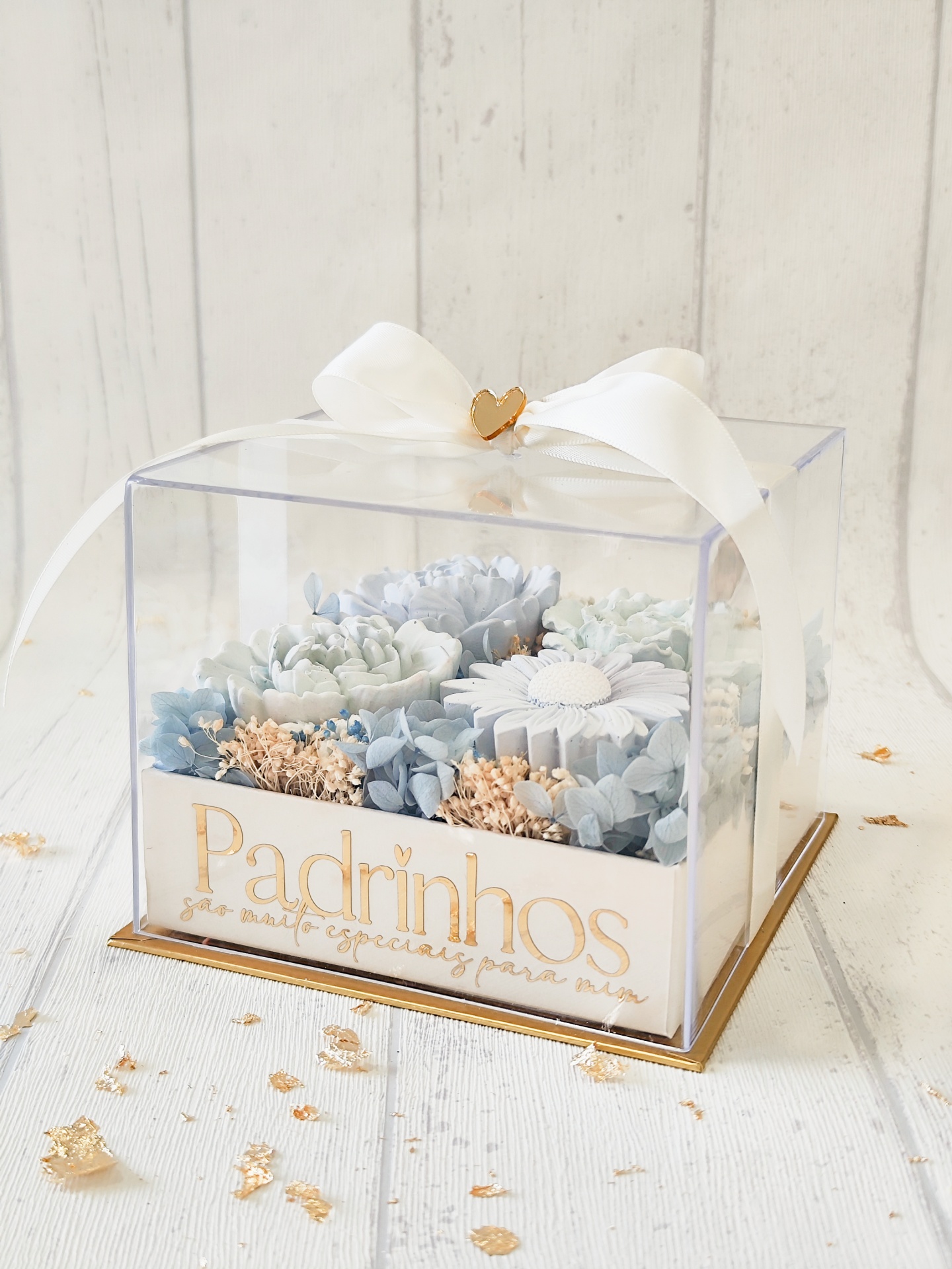 Caixa transparente com flores artificiais azuis e brancas e laço branco