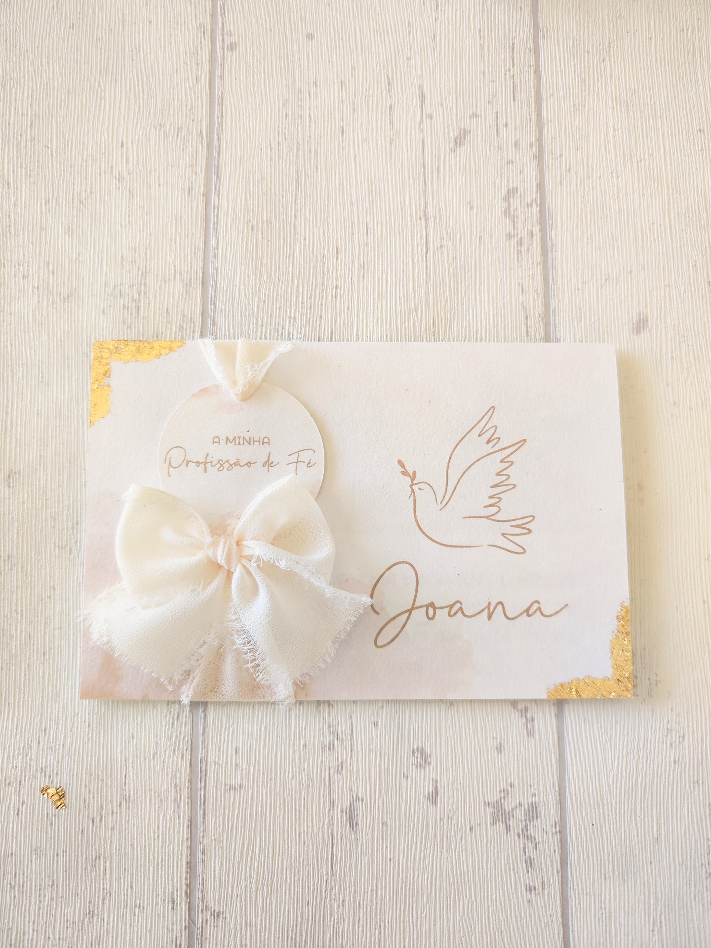 Cartão branco com bordas douradas, texto, desenho de pomba e laço de tecido branco