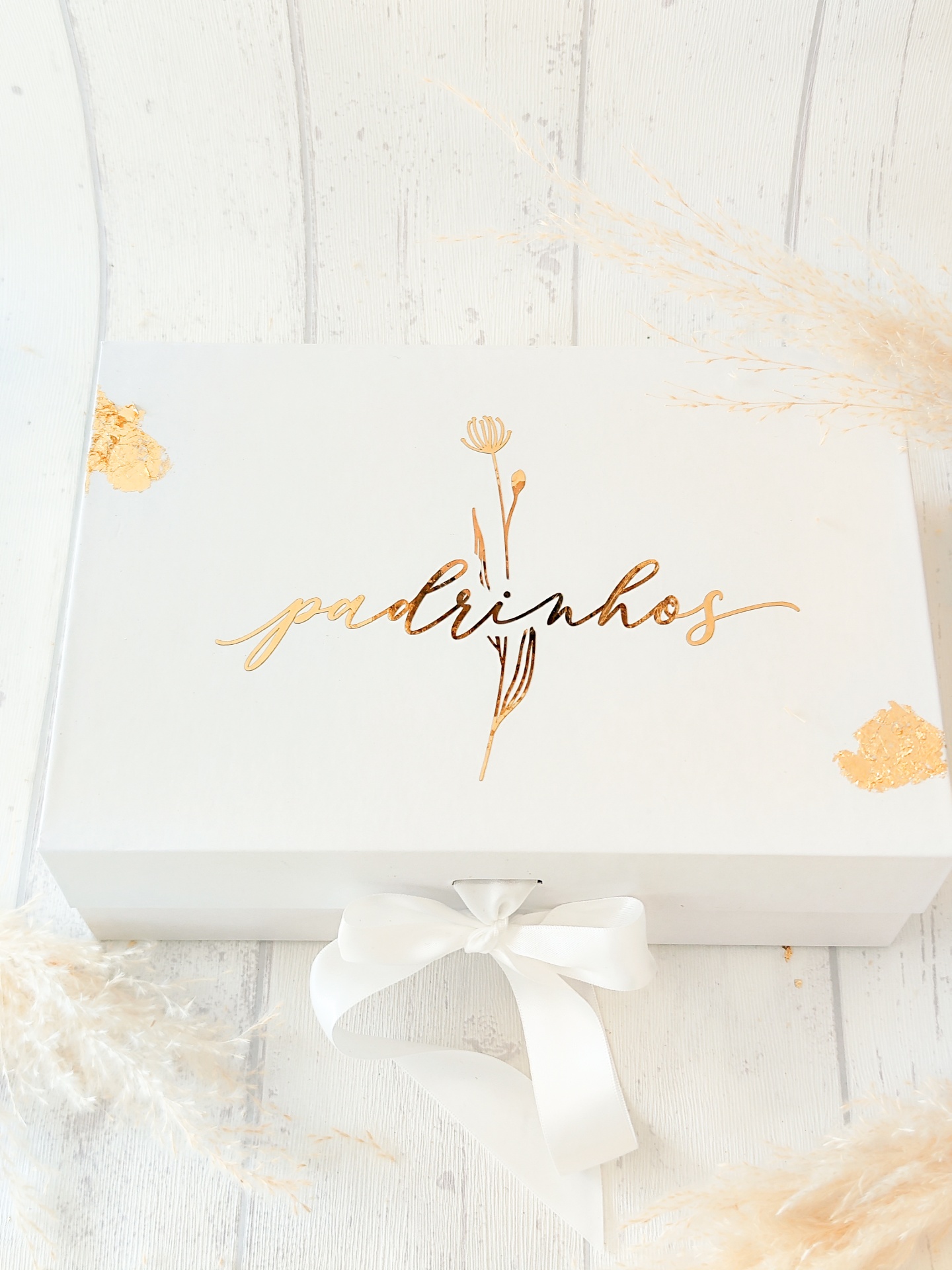 Caixa branca com texto dourado 'padrinhos' e fita branca