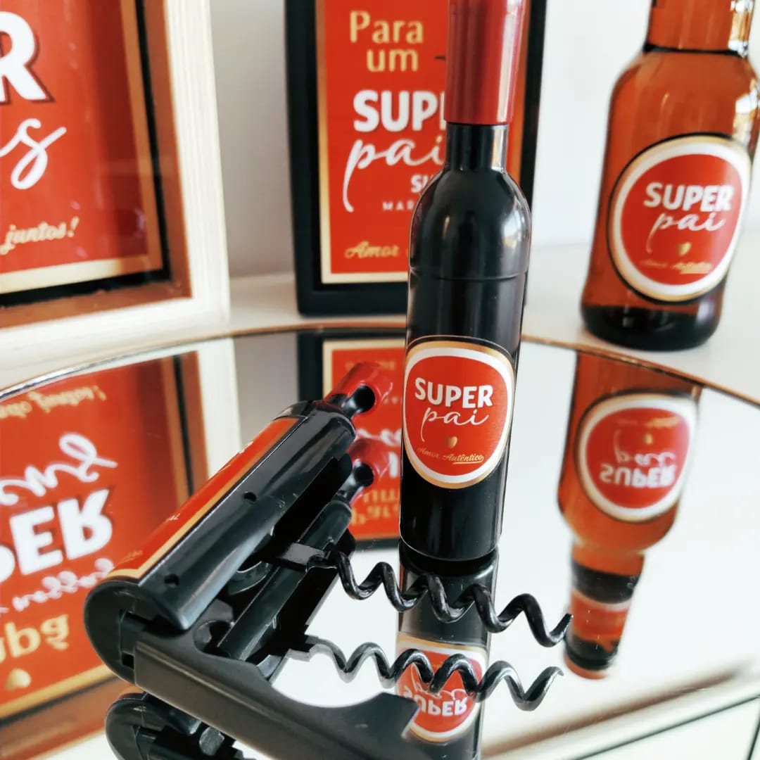 Mini garrafa de vinho com rótulo SUPER pai, saca-rolhas e cartazes vermelhos ao fundo