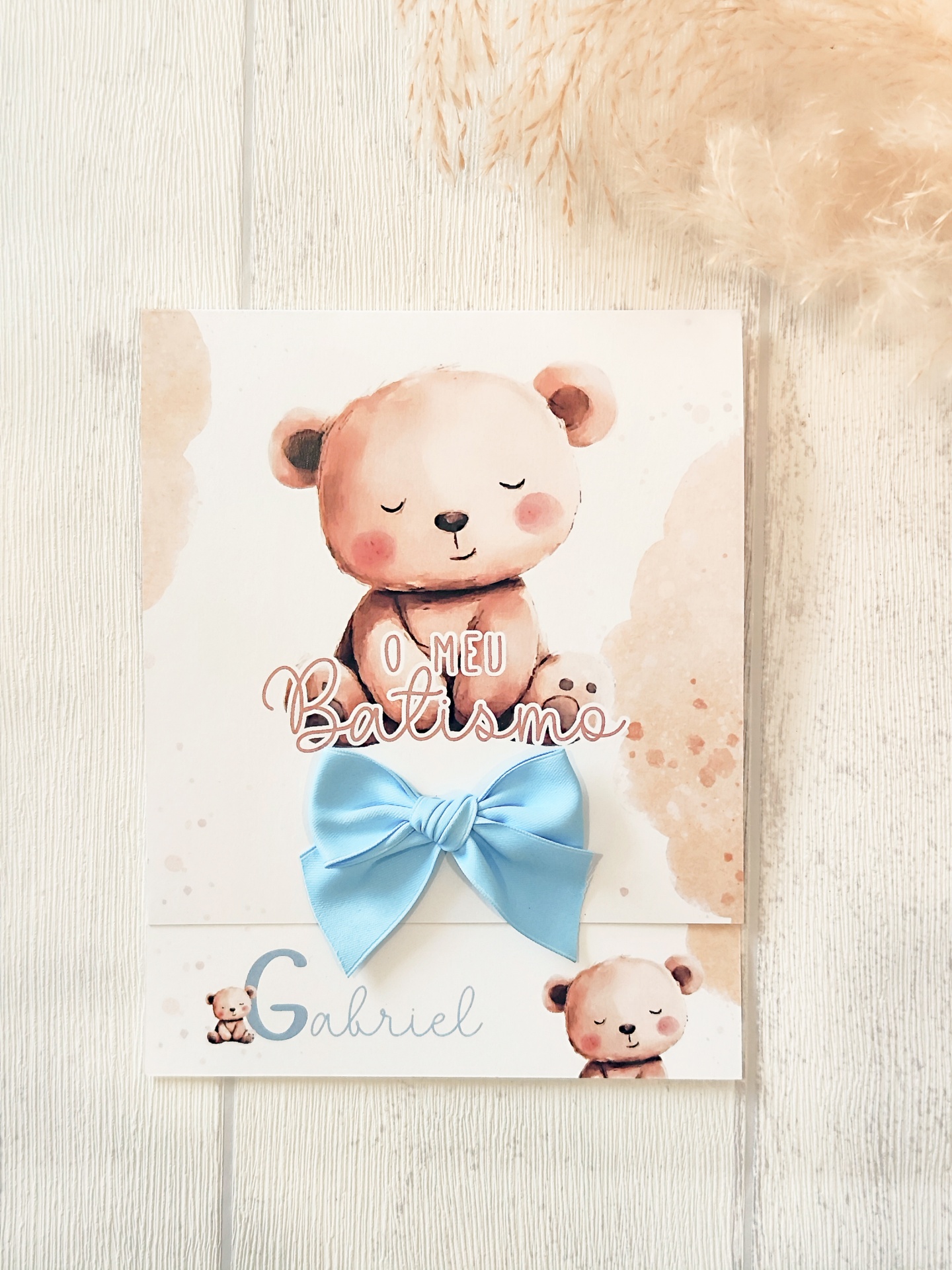 Cartão de batismo com ursinhos e laço azul sobre madeira clara