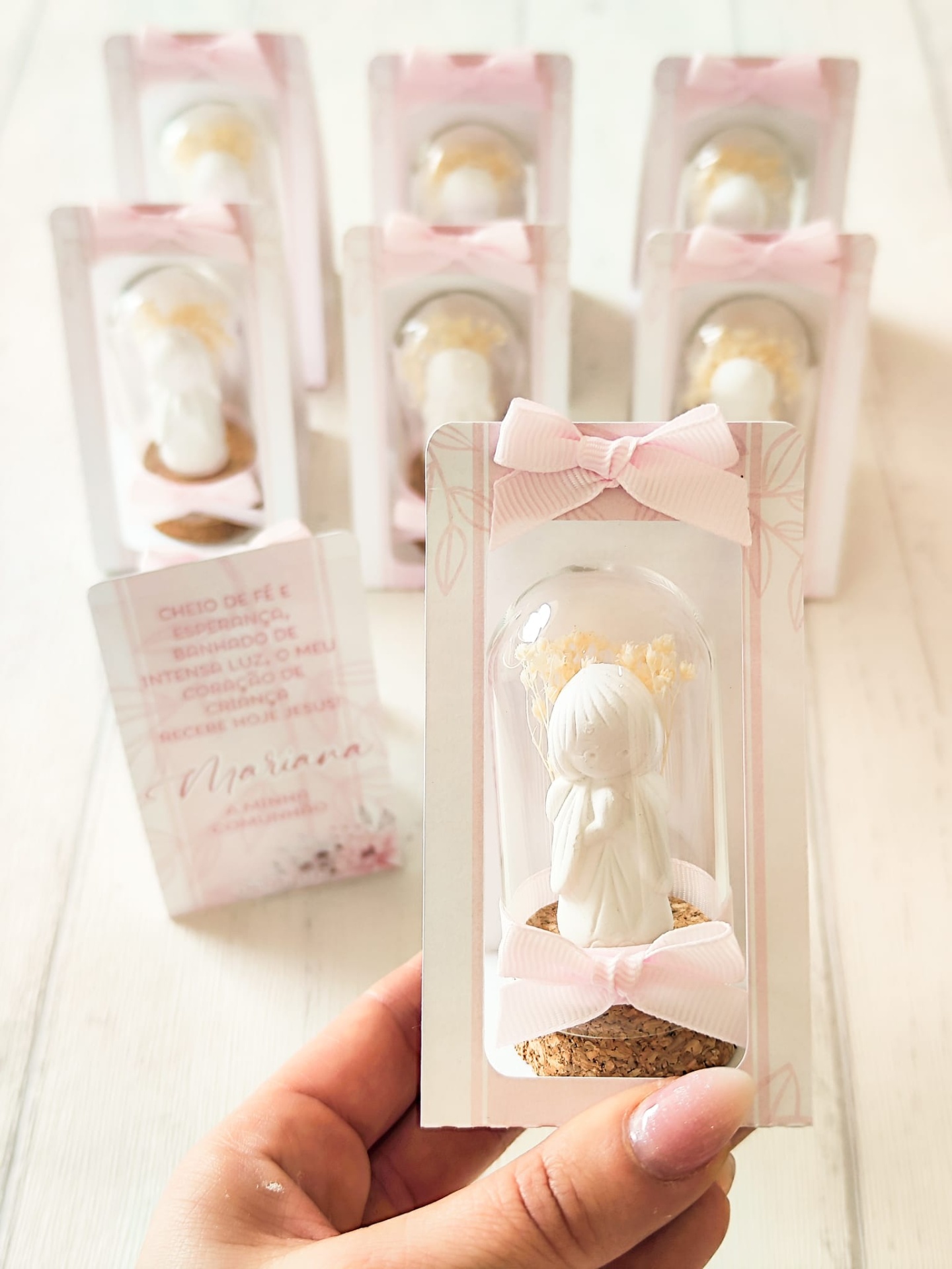 Figurinha decorativa branca com base de cortiça e laço rosa embalada em cartão rosa e branco