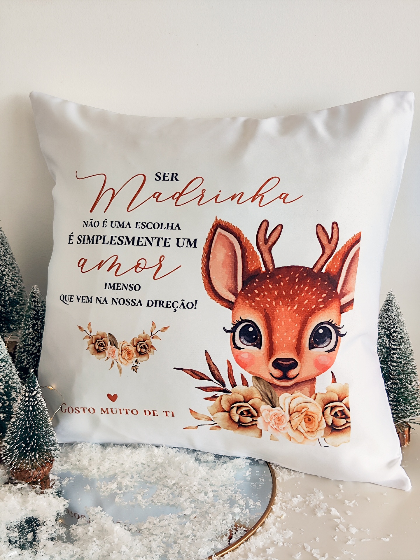 Almofada branca com desenho de cervo, flores e texto em português